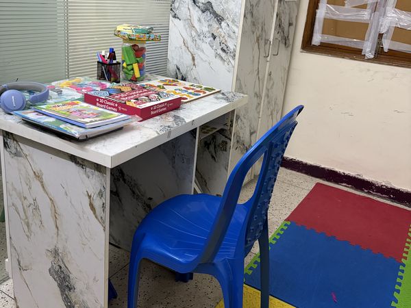 A learning desk with books and colours beside a play mat.