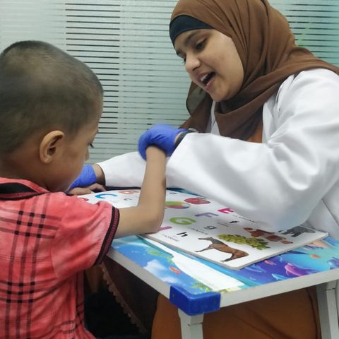 A speech therapist and a child looking at a picture book together.