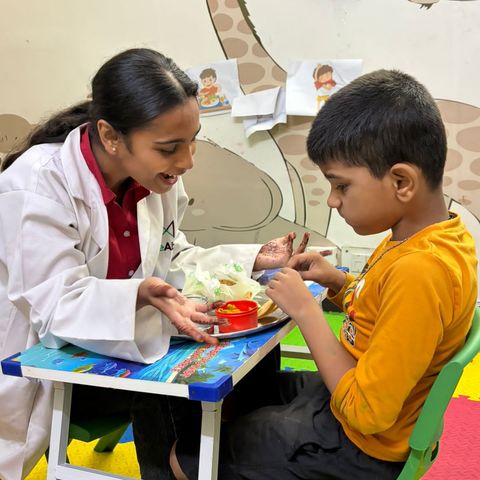 A child picking up food from a plate during an everyday-skills session.
