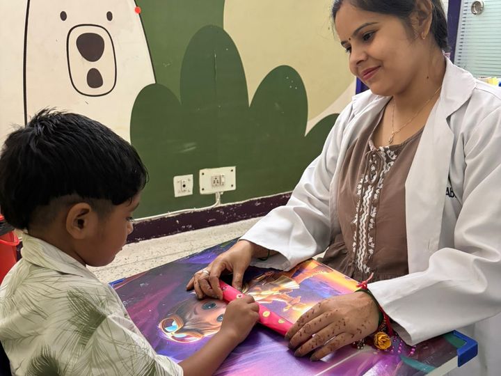 A therapist and a child drawing together at a table.