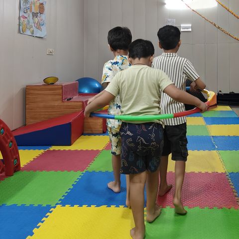 Children walking together inside a hoop in the group room.