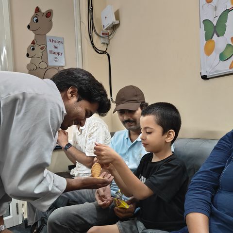 A child sitting beside an adult on a sofa while a therapist leans in.