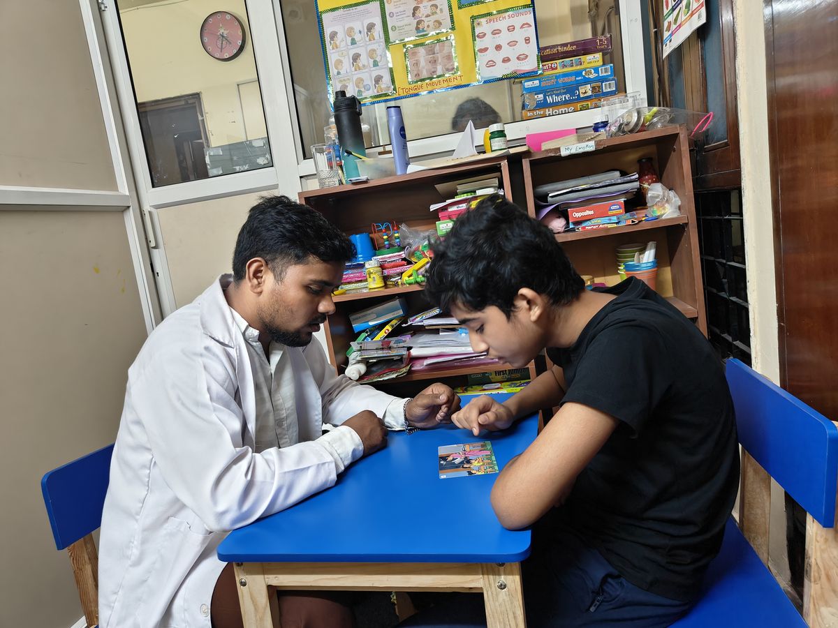 A therapist and a young person working with picture cards at a table.