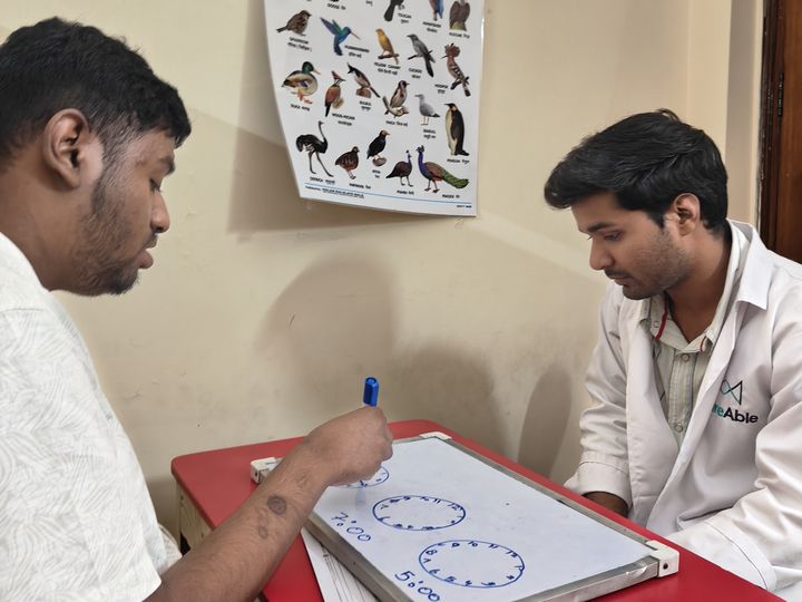 A special educator and a student working on a whiteboard at a table.