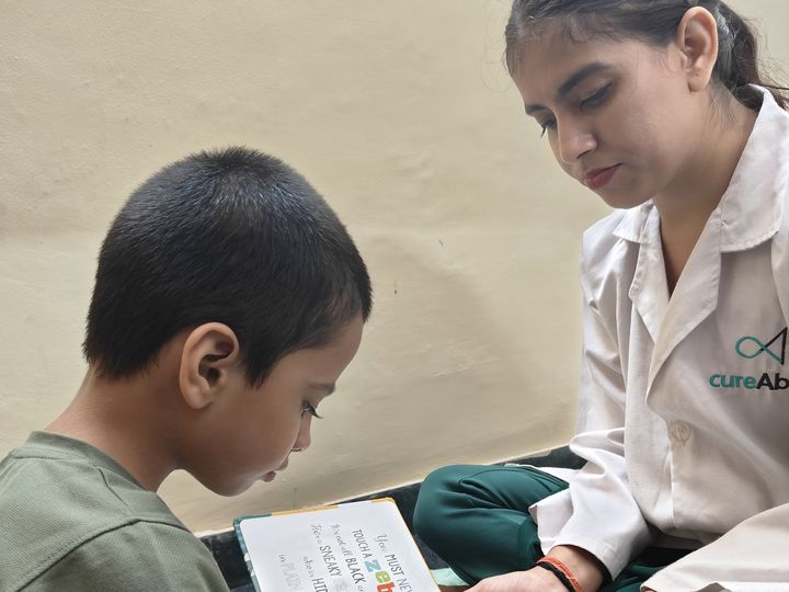 A child reading a picture book with a speech therapist.
