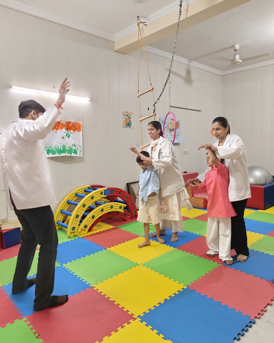Three CureAble therapists guiding children through a movement activity in the group room.