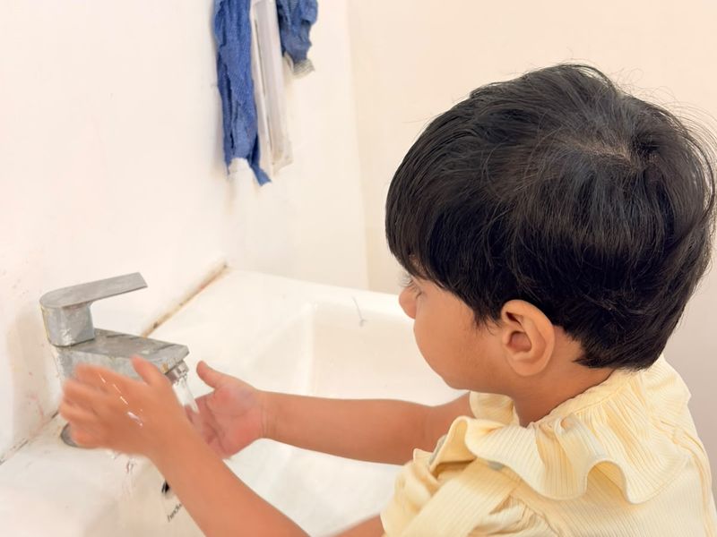 A young child washing their hands at a basin.