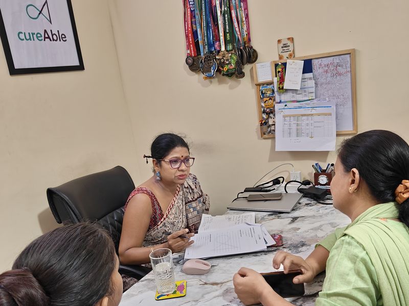 Adults talking through a plan at a desk with a CureAble counsellor.