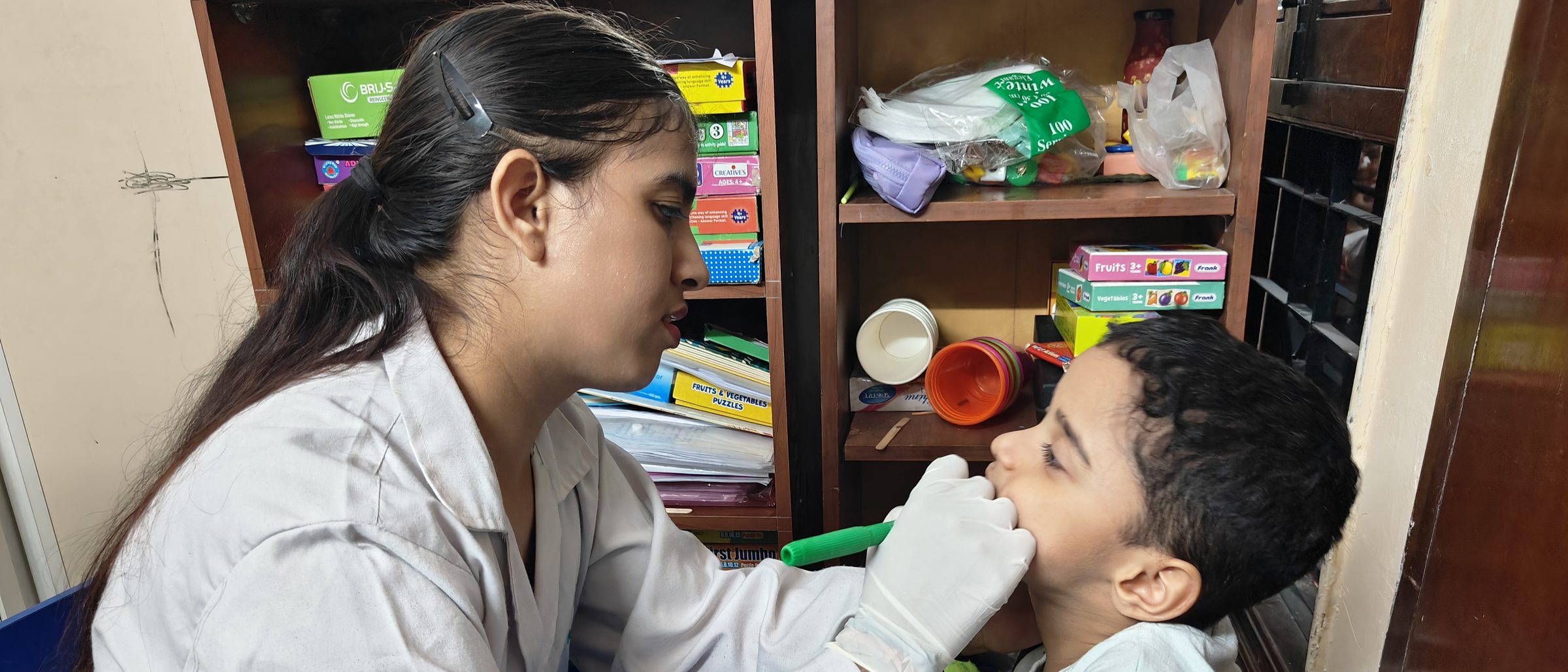A CureAble therapist works closely with a child at a blue table during a speech therapy session at the Noida Centre.
