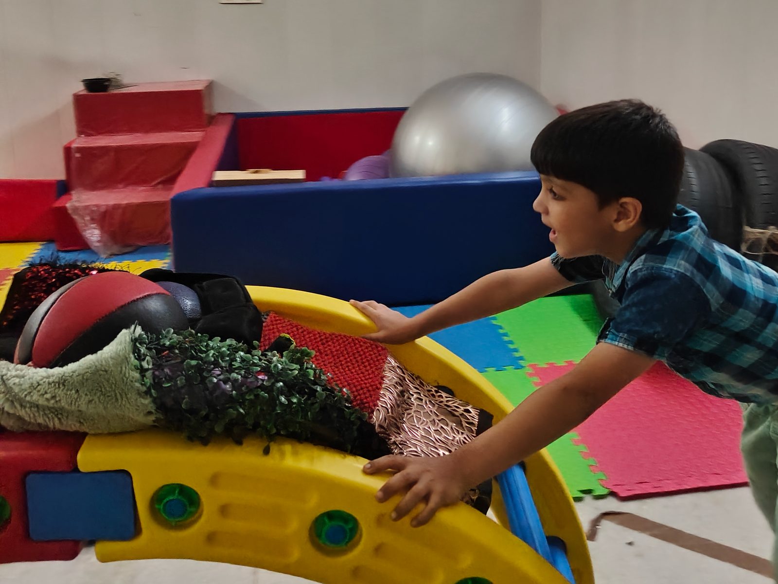 A child pushes a sensory rocker in an occupational therapy room at the Noida Centre.