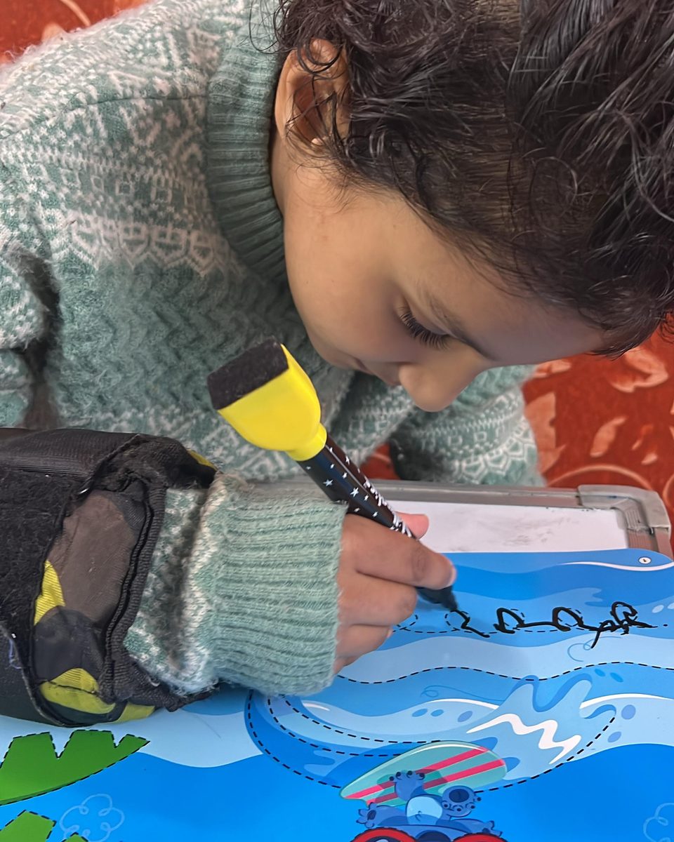 A child drawing with a marker on an illustrated activity sheet.