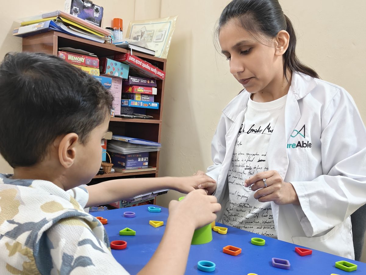 A CureAble therapist works with a child on a shape-sorting activity at a CureAble centre.