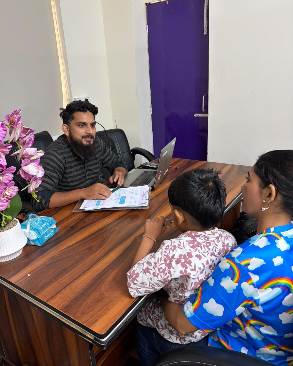 A child and two adults seated together during a discussion at the Dwarka Centre.