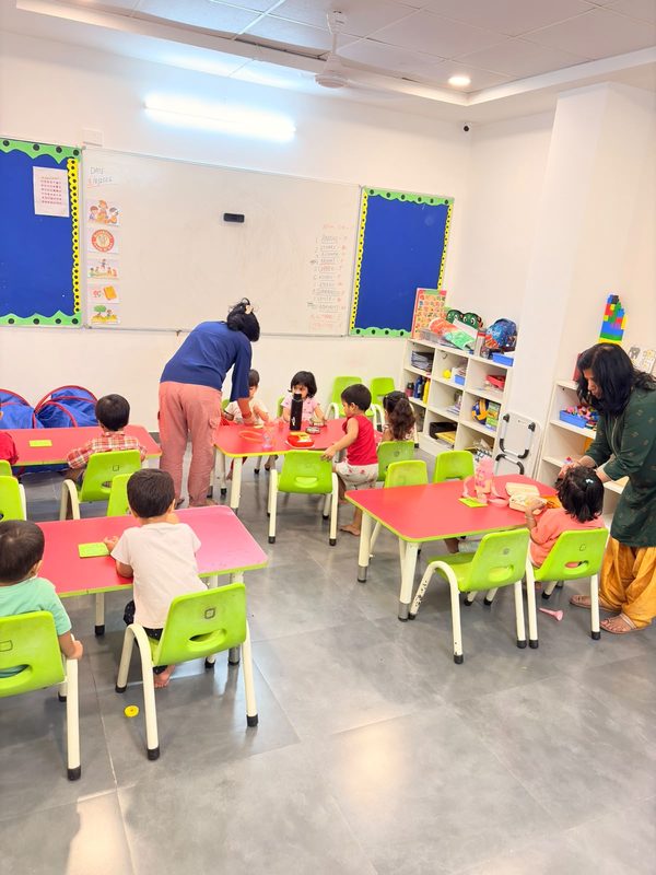 Children at classroom tables with their teachers during a learning session.