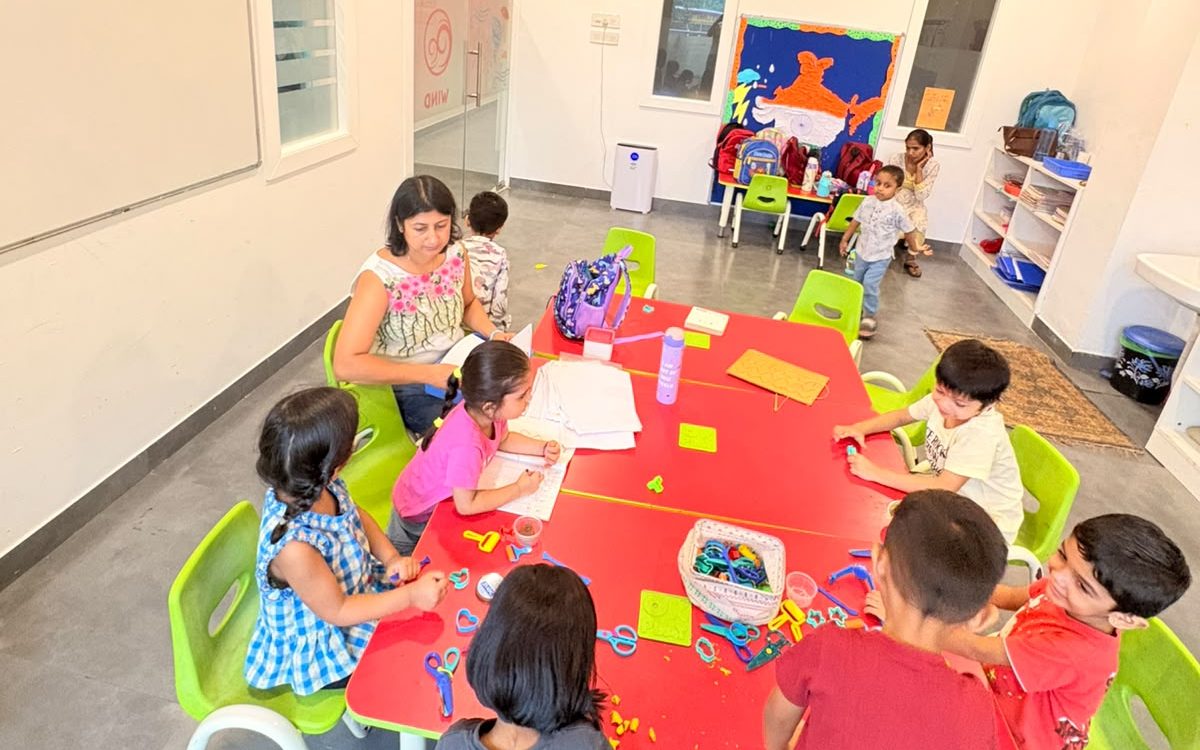 Children working together at classroom tables with their teachers.