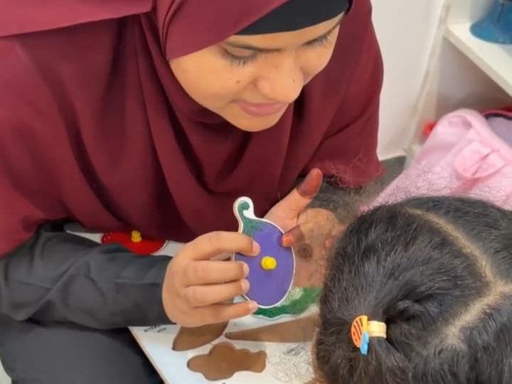 A therapist showing a young girl a picture puzzle piece.