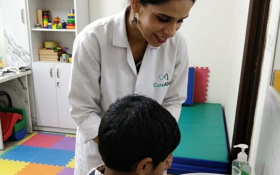 A CureAble therapist helping a child wash their hands at a basin at CureAble Dwarka.