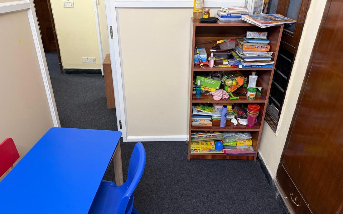 A therapy room at CureAble Noida, with a child-size blue table and chair and a shelf of games and books.