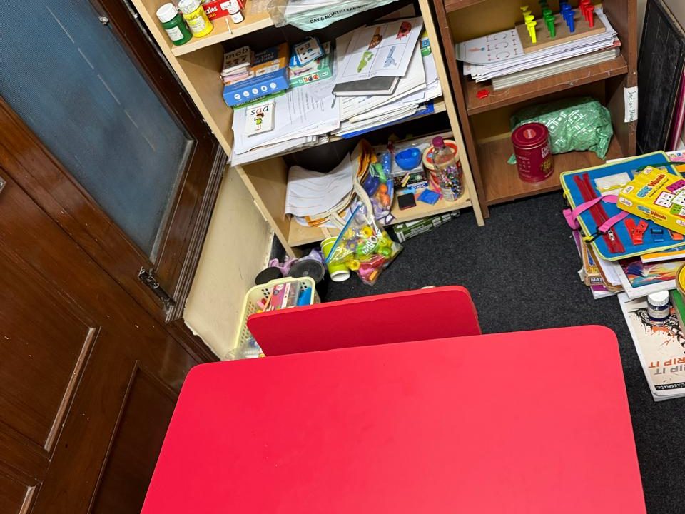 A therapy room corner at the Noida Centre, with a red child-size table and shelves of books and games.