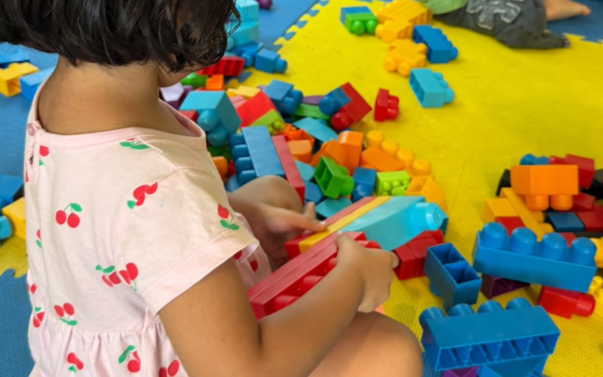 A young child exploring a pile of building blocks on a play mat at EarlyOn.