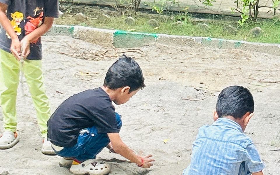 Children playing together in the sand outdoors at EarlyOn.