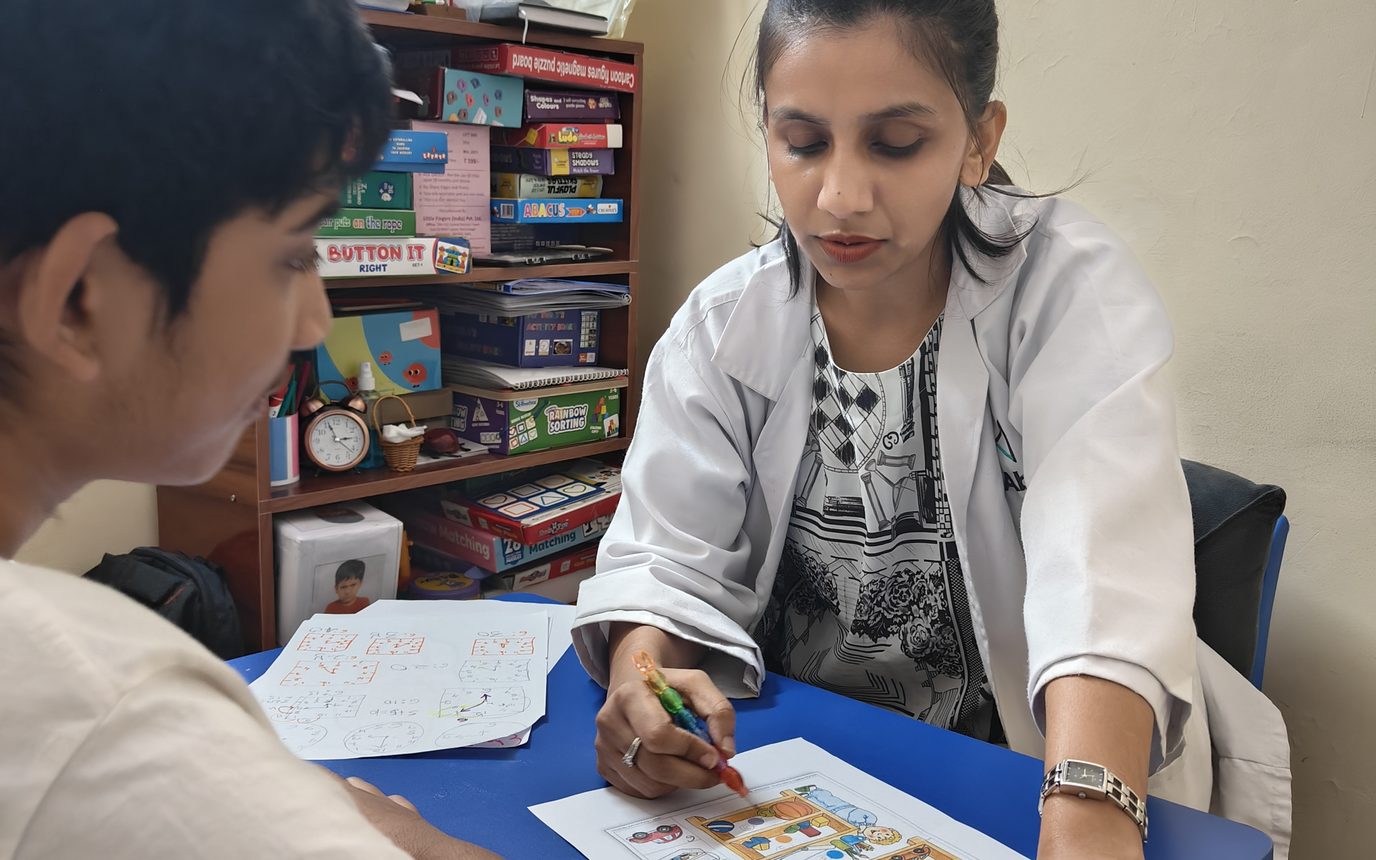 A therapist working through an activity sheet with a child at a table at the Noida Centre.