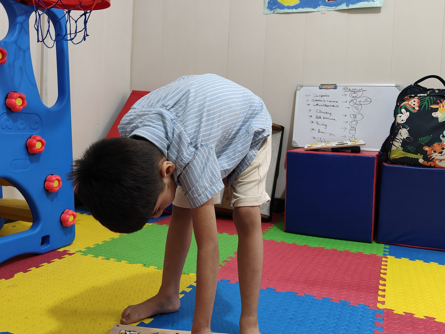 A child bending to pick up puzzle pieces from a board on the play mats at the Noida Centre.