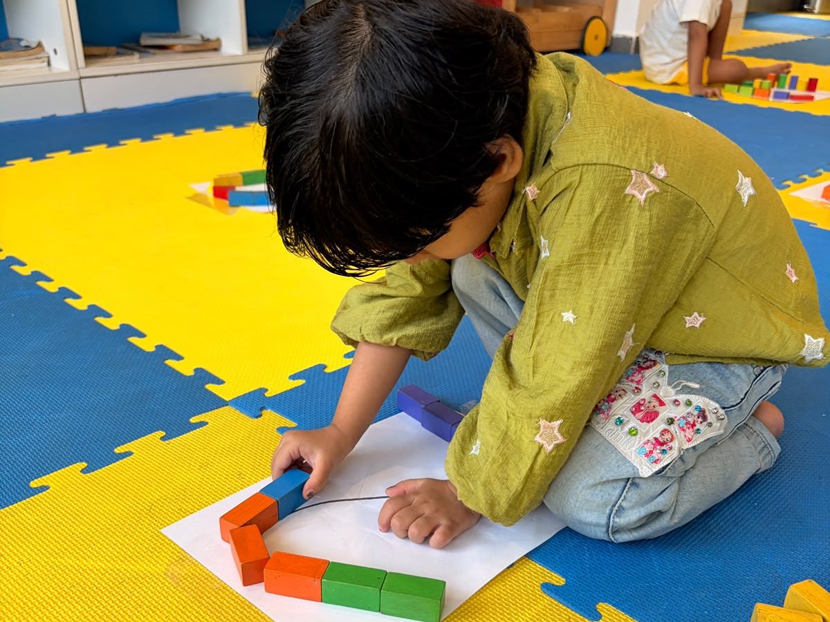 A child arranging coloured blocks on a sheet of paper on the play mats at EarlyOn.