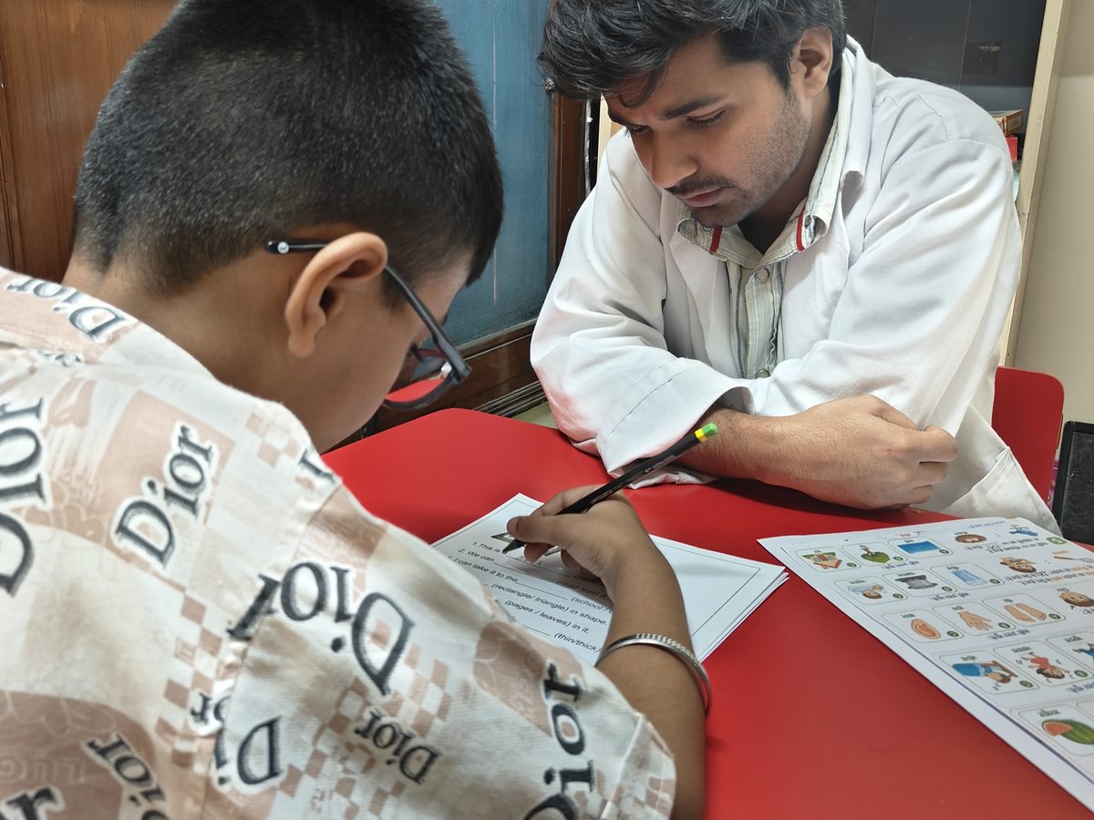 A special educator and a student working through a worksheet together at a table at the Noida Centre.